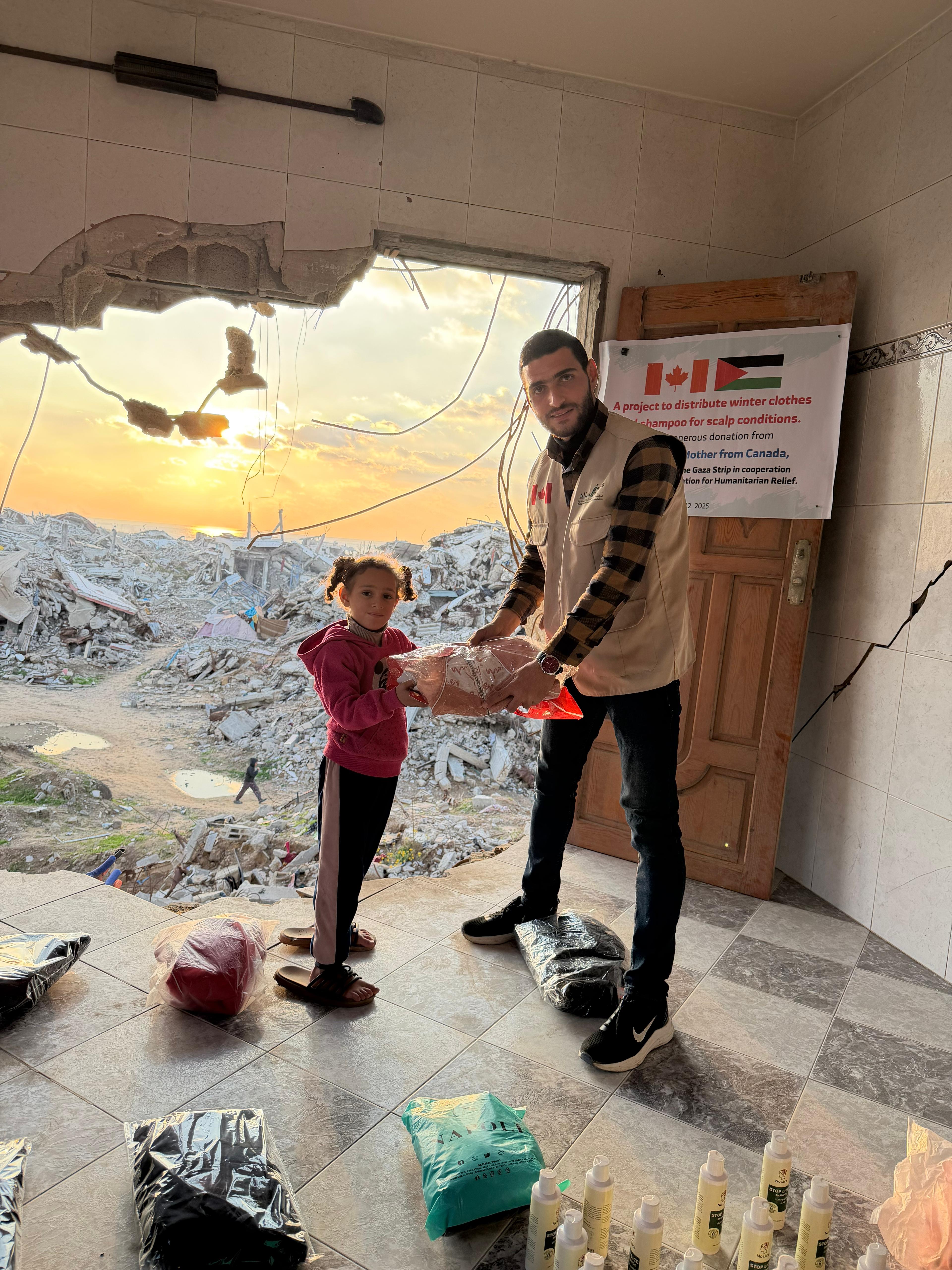 Isnad volunteer distributing winter clothes to a child in Gaza